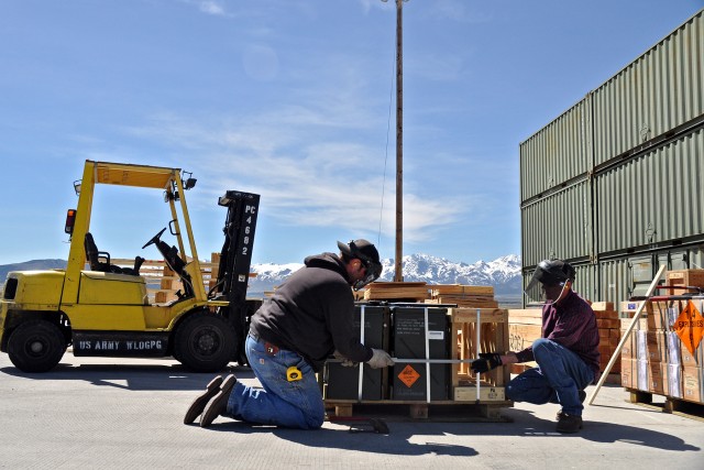 TEAD employees band a pallet of munitions