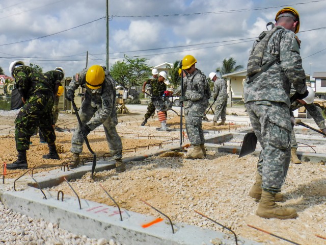 Soldiers assigned to the 672nd Engineer Company work with soldiers with the Belize Defense Force to spread and compact gravel