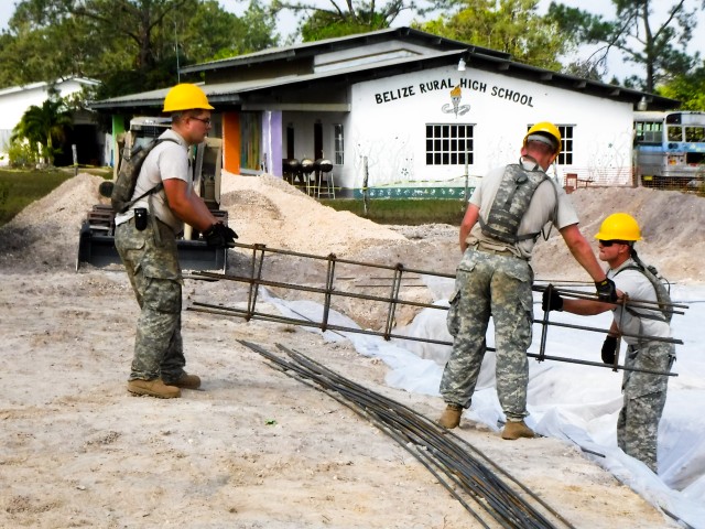 Soldiers with the 672nd Engineer Company place a rebar form cage into a cut in the ground