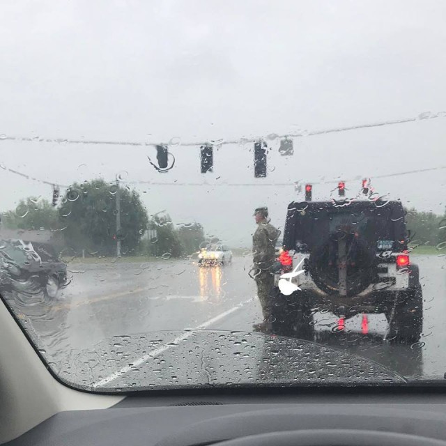 Soldier saluting funeral procession in the rain identified as Tennessee Guard colonel