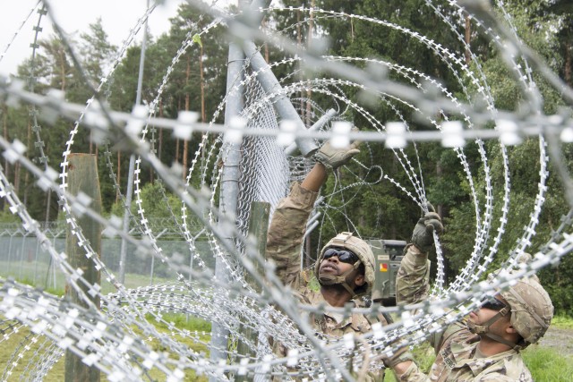 Soldiers lift concertina wire
