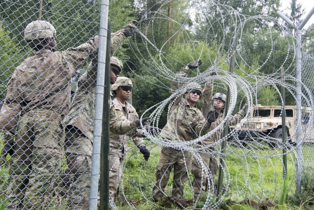 Soldiers pull the wire across the fence