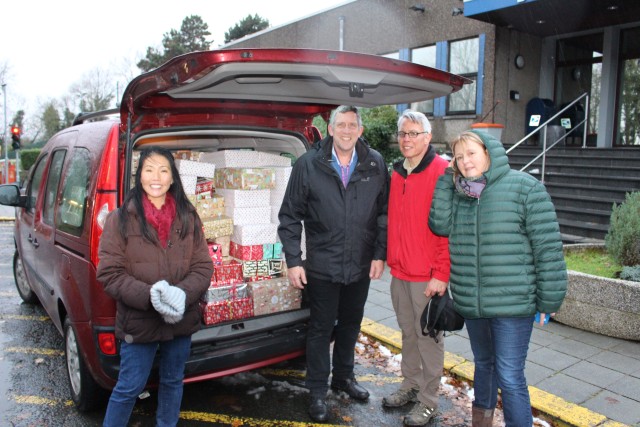 Volunteers load gift-wrapped shoe boxes in cars