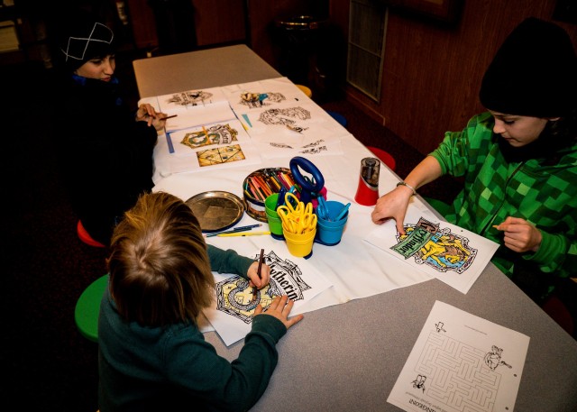 Three children color their Hogwarts house crests