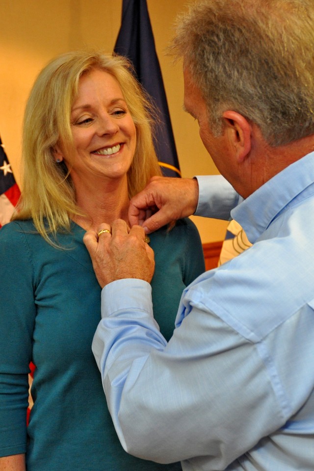 Keith Siniscalchi, civilian deputy to the commander, Tooele Army Depot, pins the Commander's Award for Public Service pin onto the collar of his wife, Frances Siniscalchi