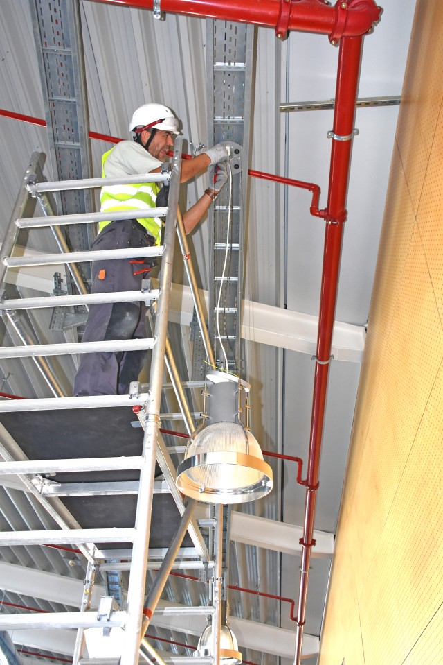 A contractor removes an old fixture from the ceiling