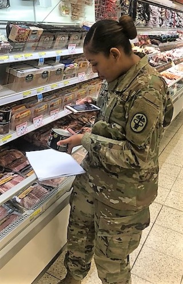 Spc. Niya Kennedy, Food Inspector Specialist from Baumholder checks lunch meat items sold at a grocery store on post.
