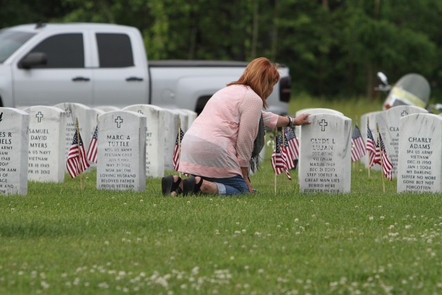 Spouse kneels at husband's grave