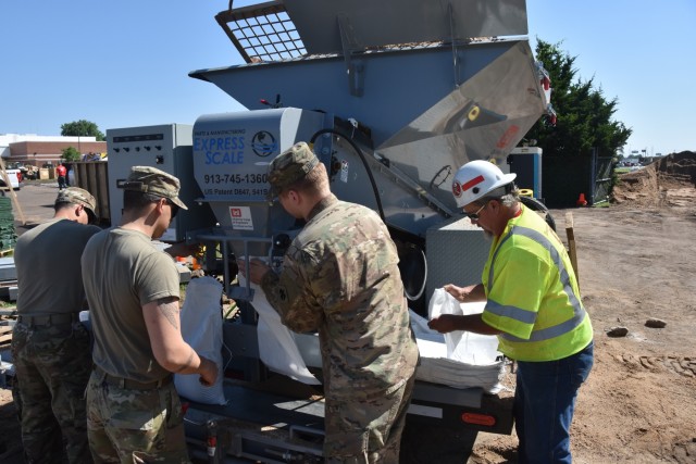 Teamwork fills sandbags along the Arkansas River