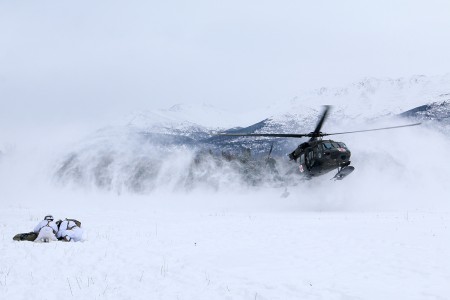 Paratroopers with 1st Squadron, 40th Cavalry Regiment (Airborne), 4th Infantry Brigade Combat Team (Airborne), 25th Infantry Division, U.S. Army Alaska, huddle over a mock casualty to protect it from the rotor-wash of a landing UH-60 helicopter at...