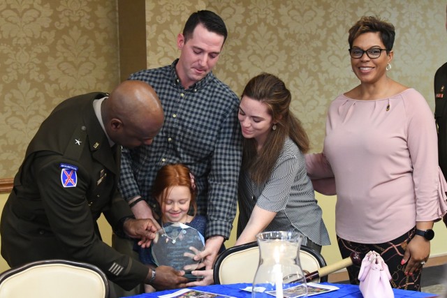 Maj. Gen. Milford "Beags" Beagle, Fort Jackson's post commander, hands out a trophy during Fort Jackson's 2019 Family of the Year Ceremony Feb. 28 at the NCO Club. Ethan Spurr (center); his wife Amanda (right); and their daughters,...