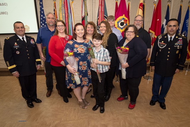 Retiree Karen Jill Puck-Grubbs (red shirt) gathers her family together for a photograph following the ceremony held March 12 in Heritage Hall, Rock Island Arsenal, Illinois. Maj. Gen. Steven Shapiro, commanding general, U.S. Army Sustainment Command, presided over the ceremony assisted by Command Sgt. Maj. Marco Torres, command sergeant major, ASC.