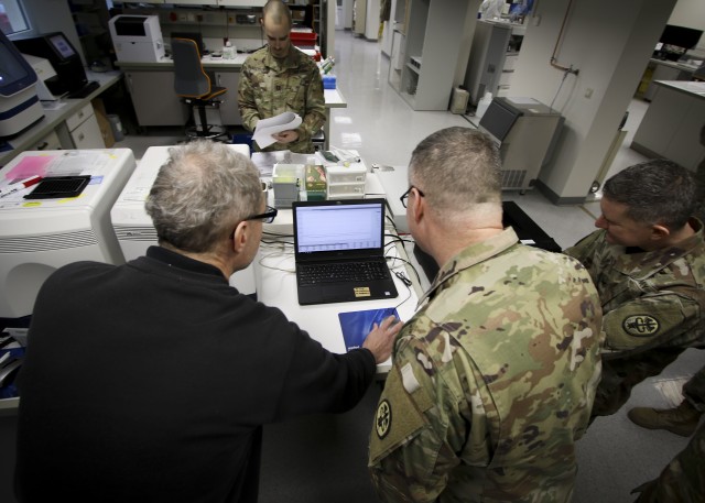 Col. Michael Weber and Command Sgt. Maj. Thurman Reynolds, Landstuhl Regional Medical Center command team, speak with Dr. Michael Koenig, technical supervisor, Virology Laboratory, to learn about LRMC’s Centers for Disease Control and Prevention...