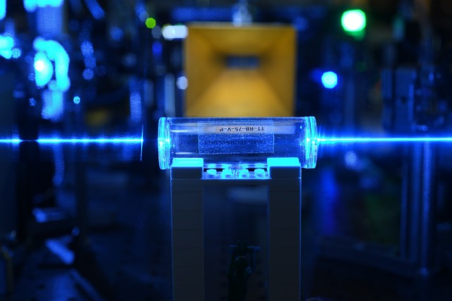 Atoms in a glass vapor cell are excited with laser beams to Rydberg states. They detect the electric fields (coming from the gold antenna in the background) and imprint the information back onto the laser beams.