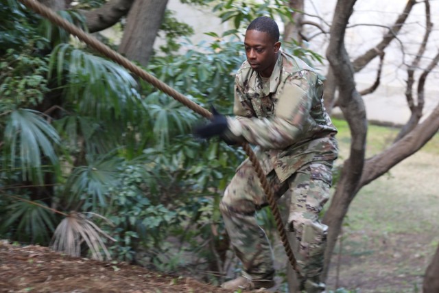 Sgt. 1st Class Willie Williams, first sergeant of U.S. Army Japan’s Headquarters and Headquarters Company, climbs a hill using a rope during physical training his unit conducted on the newly built obstacle course on Camp Zama March 20. (U.S....