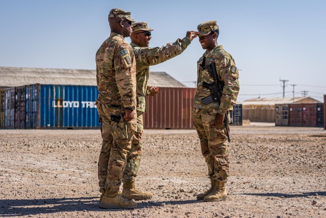 Capt. Marcus Smith and 1st Sgt. James Delaney, Headquarters Company command team, 529th Support Battalion, promote Roger Jackson from sergeant to staff sergeant at Camp Taji, Iraq, July 27, 2019. 