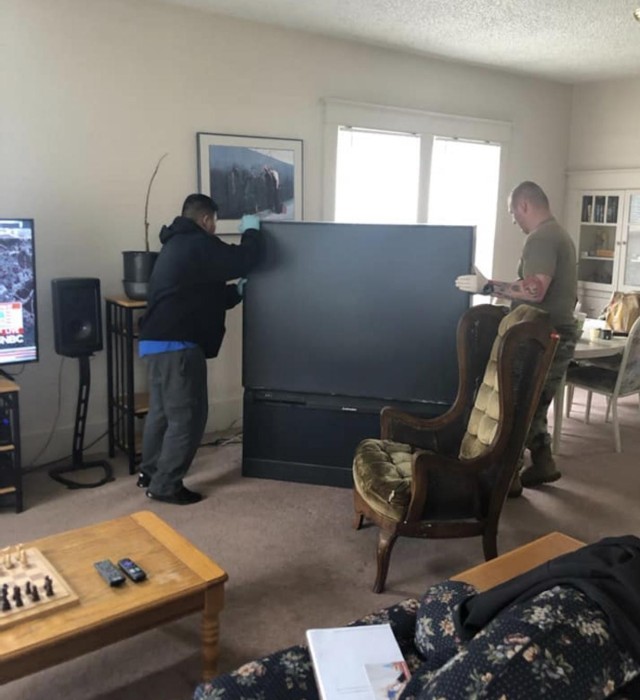 Sgt. 1st Class Rey Bagorio (left) and Capt. Tony Storey, both assigned to the Warrior Transition Battalion, Joint Base Lewis McChord, work together to move a television as they prepare a room for a homeless veteran. (U.S. Army courtesy photo)