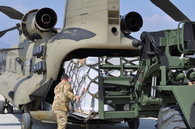 Soldiers from the U.S. Army Medical Materiel Center-Korea's 563rd Medical Logistics Company loads Class VIII medical supplies onto a CH-47 helicopter with guidance from the 2ID/2CAB crew chief on March 24, 2020. (U.S. Army photo by Shawn Hardiek)