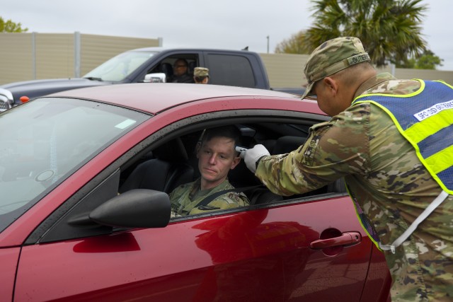 Sgt. 1st Class Genaro Gutierrez, a Fort Jackson drill sergeant, takes the temperature of 1st Sgt. Timothy Kotchian of Company A, 3rd Battalion, 39th Infantry  Regiment, at the installation main gate on March 24. Temperatures and questioning are heightened security measure at Fort Jackson to help prevent the spread of COVID-19.