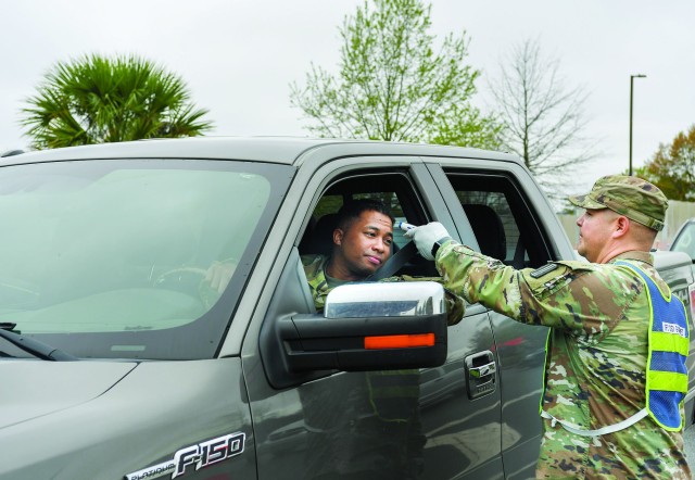 Sgt. 1st Class Genaro Gutierrez, a Fort Jackson drill sergeant, takes the temperature of Capt. Jay Banks of Company A, 4th Battalion, 39th Infantry Regiment, at the installation main gate on March 24. Temperatures and questioning are heightened security measure at Fort Jackson to help prevent the spread of COVID-19.
