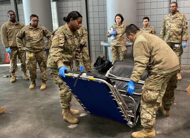New York Army National Guard Soldiers with the 133rd Composite Supply Company demonstrate assembling a cot at the Jacob K. Javits Convention Center in New York City March 26, 2020. The convention center will be an alternate care site to ease the bed shortage of New York Hospitals as part of the state response to the COVID-19 outbreak.
