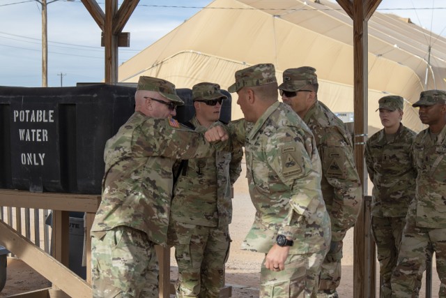 Maj. Gen. Frank Tate, commanding general of First Army Division West, greets Col. Michael Trotter, commander of 1st Brigade Combat Team, 1st Armored Division, with the “Big A Elbow.”  First Army Soldiers follow Center for Disease Control and Prevention guidelines by minimizing physical contact to control the spread of COVID-19.  (U.S. Army photo by Staff Sgt. Timothy Gray, 5th Armored Brigade)