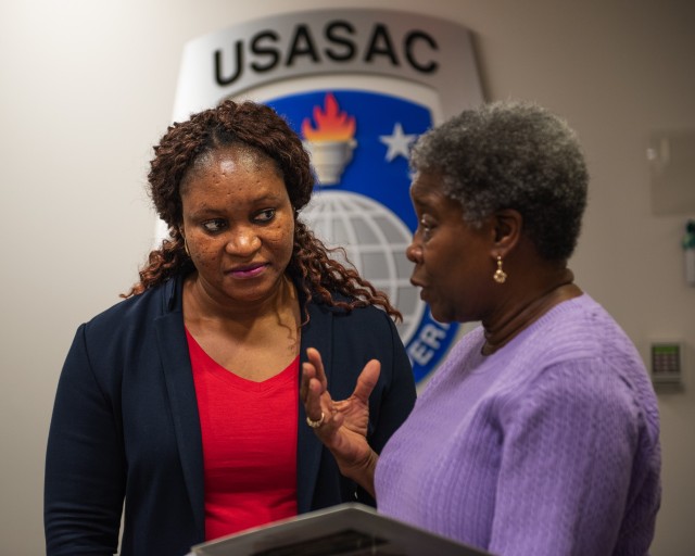 Oluwatoyin Adeyemo, left, listens to her mentor, Elsa Stuart, at U.S. Army Security Assistance Command headquarters at Redstone Arsenal, Alabama. (Photo by Richard Bumgardner, USASAC)