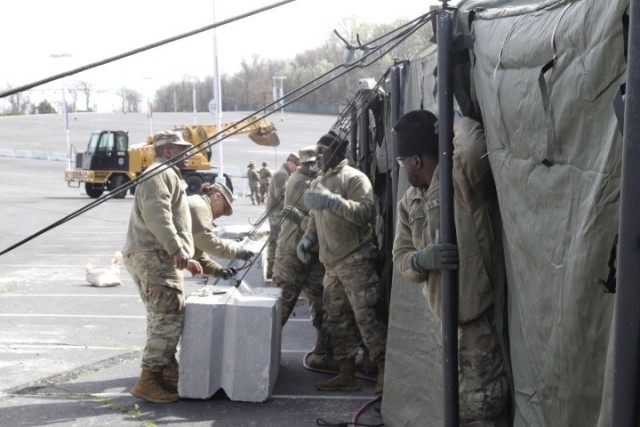 Soldiers in the Maryland National Guard&#39;s 1229th Transportation Company install a tent at the FedEx Field parking lot in preparation for COVID-19 testing in Landover, Maryland, March 21, 2020. Part of Maryland National Guard’s response, the site is one of several that continue to stand up across the country as Soldiers swap in their weapons for masks and gloves. 