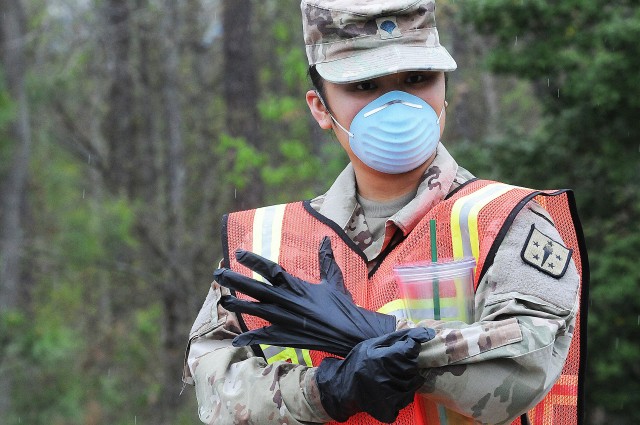 Spc. AprilJeremy Monis, Headquarters and Headquarters Company, 59th Ordnance Brigade, adjusts protective gloves while awaiting the arrival of several buses of basic combat training graduates scheduled to arrive at Fort Lee from Fort Jackson, S.C. March 31.  Just over 800 troops arrived here shortly after to continue their initial entry training. To prevent the spread of COVID-19, they were placed on sterilized buses, seated in spaced-apart intervals, medically screened before departure and upon arrival, and accompanied by cadre members from Fort Jackson.