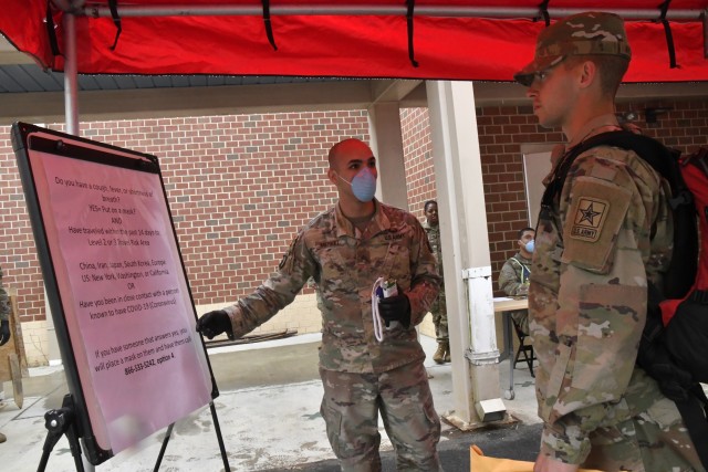 Sgt. Devon Merkel of the 59th Ordnance Brigade stands by as a basic combat training graduate reads a list of questions March 31 that are part of the COVAID-19 screening process for newly-arrived troops at Fort Lee. The new troop was one of 800 transported here to continue their initial entry training. To prevent the spread of COVID-19, they were placed on sterilized buses, seated in spaced-apart intervals, medically screened before departure and upon arrival, and accompanied by cadre members from Fort Jackson.