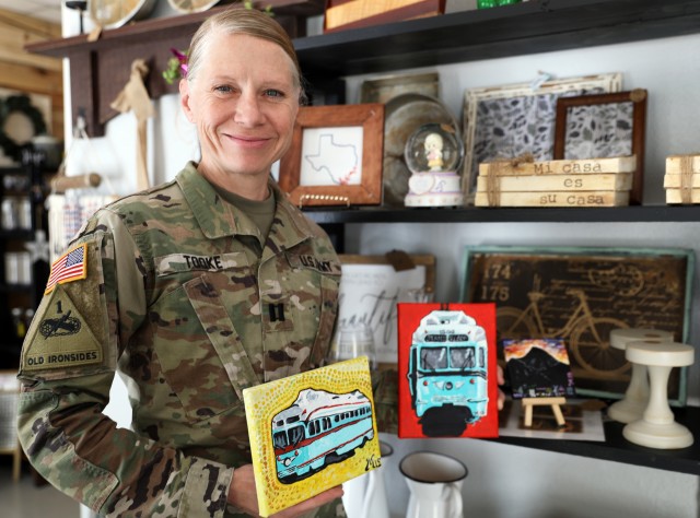 Fort Bliss, Texas - El Paso native Capt. Amanda Tooke, Alpha Company Commander of the Warrior Transition Battalion, William Beaumont Army Medical Center, displays her paintings of El Paso streetcars in the A Little Bit of Bliss gift shop, on Feb. 6. A service member and a military spouse, Tooke is one of several vendors that has sold her pieces at the gift shop which aims to help military spouses find jobs, build careers and improve their quality of life. (U.S. Army photo by Jean S. Han)