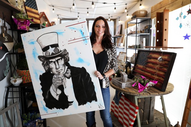 Fort Bliss, Texas - Misty Hofmann, a native of Mount Dora, Florida, spouse of Lt. Col. Patrick Hofmann, Headquarters and Headquarters Battalion, 1st Armored Division, displays her painting of Uncle Sam inside the A Little Bit of Bliss gift shop on Feb. 6. The shop has become a haven for military spouses looking for a creative outlet, hobby, comradery or employment. Aside from independent opportunities like A Little Bit of Bliss, the Army is taking an active approach to help military spouses find jobs, build careers and improve their quality of life. (U.S. Army photo by Jean S. Han)