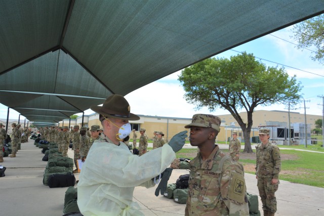 Drill Sergeant Jeremey Shepler, the Senior Drill Sergeant for the Medical Professional Training Brigade, takes the temperature of a 68W Combat Medic arriving from Fort Sill, OK to begin their advanced individual training at Fort Sam Houston, TX.