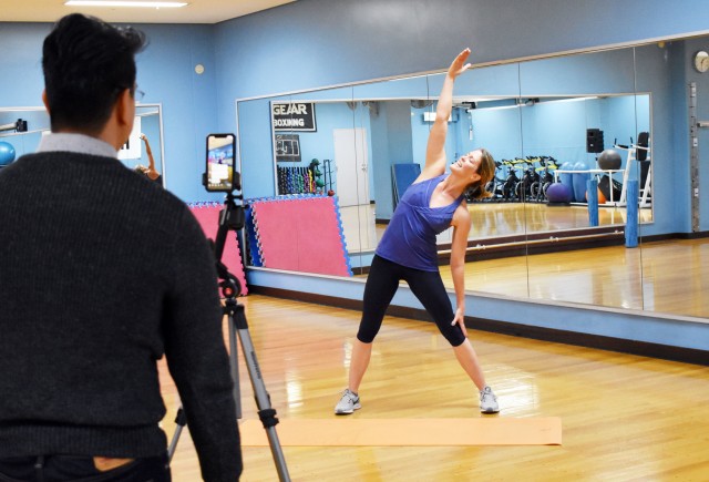 Jess Kotleski, a volunteer fitness instructor for Family and Morale, Welfare and Recreation, U.S. Army Garrison Japan, holds a livestreamed “No Bore, Core and More” class at Camp Zama, Japan, April 2, 2020. Marenzo Domingo, left, marketing...