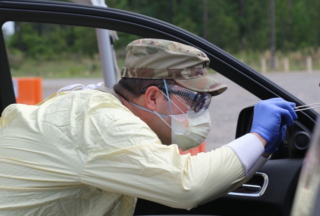 Pfc. Jordan Tovarnak, a combat medic from the 1st Armored Brigade Combat Team, 3rd Infantry Division, collects a sample from a patient’s mouth at the drive-thru screening site at Fort Stewart, Ga., April 7, 2020.  The drive-thru screening process helped screen and test patients for COVID-19, without the need for them to leave their vehicles. This allowed cross infection prevention by keeping people, who wanted to be tested, from gathering in large groups at medical facilities.