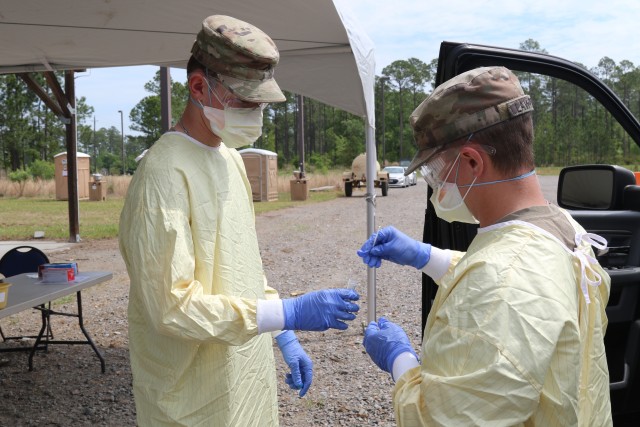 Pfc. William Lawrence and Pvt. Anthony Blau, combat medics from the 1st Armored Brigade Combat Team, 3rd Infantry Division prepare and seale a swab to be sent to a lab for testing at the drive-thru screening site at Fort Stewart, Ga., April 7, 2020. The drive-thru screening process helped screen and test patients for COVID-19, without the need for them to leave their vehicles. This allowed cross infection prevention by keeping people, who wanted to be tested, from gathering in large groups at medical facilities.