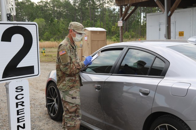 Pvt. Ryan Burnside, a combat medic with the 2nd Battalion, 7th Infantry Regiment, 1st Armored Brigade Combat Team, 3rd Infantry Division, screens a patient at the drive-thru screening site at Fort Stewart, Ga., April 7, 2020. The drive-thru screening process helped screen and test patients for COVID-19, without the need for them to leave their vehicles. This allowed cross infection prevention by keeping people, who wanted to be tested, from gathering in large groups at medical facilities.