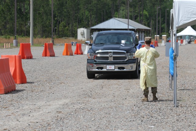 Pfc. William Lawrence, a combat medic from the 1st Armored Brigade Combat Team, 3rd Infantry Division, guides a vehicle to his testing location  at the drive-thru screening site at Fort Stewart, Ga., April 7, 2020.  The drive-thru screening process helped screen and test patients for COVID-19, without the need for them to leave their vehicles. This allowed cross infection prevention by keeping people, who wanted to be tested, from gathering in large groups at medical facilities.