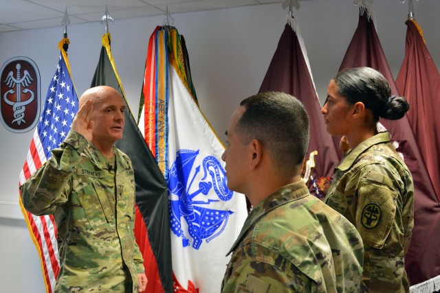 Brig. Gen. Ron Stephens, the Regional Health Command Europe commanding general, delivers the oath of enlistment to Staff Sgt. Carlos and Jamie Castillo.