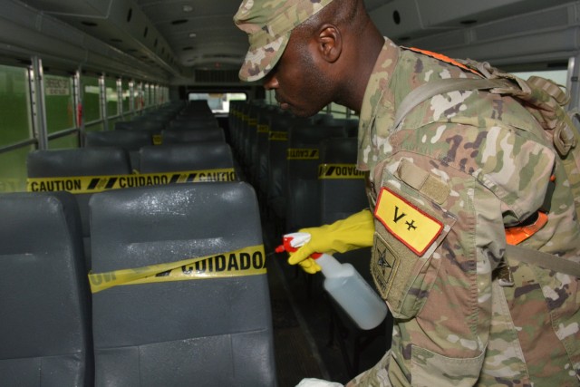 A Soldier assigned to the 232d Medical Battalion sanitizes a bus prior to other Soldiers boarding. The Soldiers were transported in controlled air and ground movements to their next duty of assignment as an exception to the Department of Defense stop movement enacted to stop the potential spread of the 2019 Coronavirus Disease, or COVID-19.