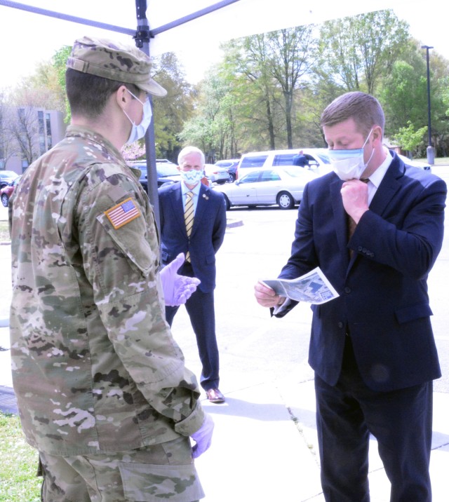 Secretary of the Army Ryan D. McCarthy tugs his protective face mask into place and reads through COVID-19 screening questions prior to entering Kenner Army Health Clinic during an April 8 tour of Fort Lee, Va. McCarthy was accompanied by Sgt. Maj. of the Army Michael A. Grinston. The clinic visit allowed them to get a better perspective on how the military health facility is responding to the pandemic. In addition to entrance screening, Kenner has installed sneeze guards at customer service desks, curtailed walk-in services and all prescription are drop-off and next-day drive-thru pickup only. (Photo by Tammy L. Reed)