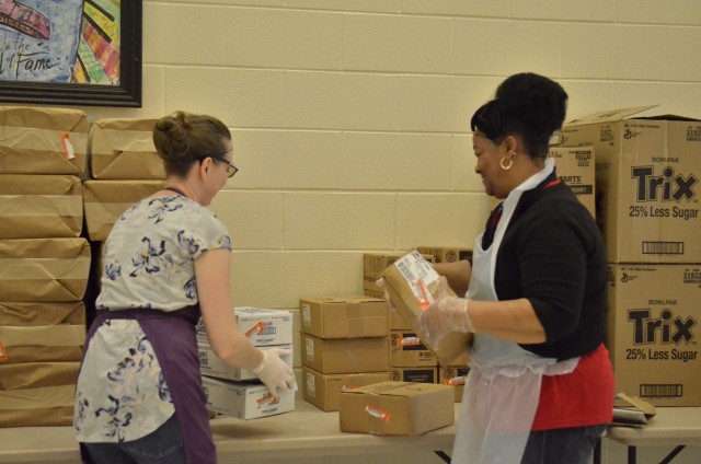 Megan Perez, administrative assistant for the Fort Campbell Child Nutrition Program, and Glenda Morris, executive cook at Marshall Elementary School, help package free grab-and-go breakfast and lunch meals for children age 18 and younger at...