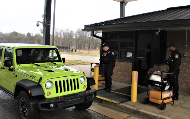 Officers Mark Johnson and Emanuel Brown with the Directorate of Emergency Services Police Department review a motorist’s ID and asks screening questions April 3, 2020, at the Main Gate entry control point at Fort McCoy, Wis. Fort McCoy police have limited entry to the installation since the start of the installation’s response to the COVID-19 pandemic in March 2020. (U.S. Army Photo by Scott T. Sturkol, Public Affairs Office, Fort McCoy, Wis.)