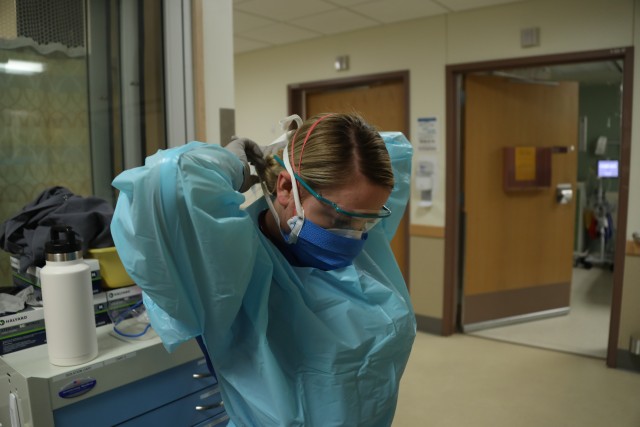 JOINT BASE LEWIS-MCCHORD, Wash. – A medical-surgical nurse with the Madigan Army Medical Center Emergency Department, 1st Lt. Sarah Hendricks, dons a face mask before seeing a patient in the emergency room at JBLM, April 9, 2020. To assist with the shortage of personal protective equipment on post, parachute riggers with 1st Special Forces Group (Airborne), Group Support Battalion, used their equipment and facilities to fabricate face masks with sterile, one-time use only cloth for the Madigan hospital.