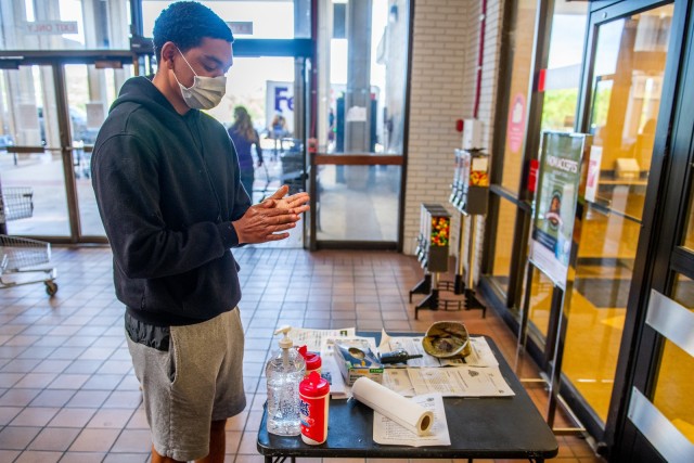 FORT BENNING, Ga. – At the entrance to Fort Benning's commissary April 15, a customer cleans his hands with sanitizer placed there for patron's use, and, in keeping with a recent Department of Defense directive, wears a face mask before entering...