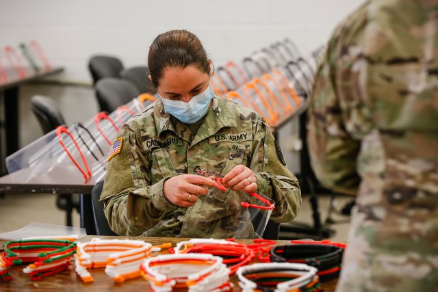 Pfc. Dainerys Caballero, a signal support systems specialist with the 18th Field Artillery Brigade, finishes assembling a face shield at Fort Bragg, N.C., on April 15, during Operation Dragon Mask. Units from across Fort Bragg were repurposed to create face masks, face shields, and other personal protective equipment to be distributed as part of the COVID-19 response. (U.S. Army Photo by Spc. Hubert D. Delany III)