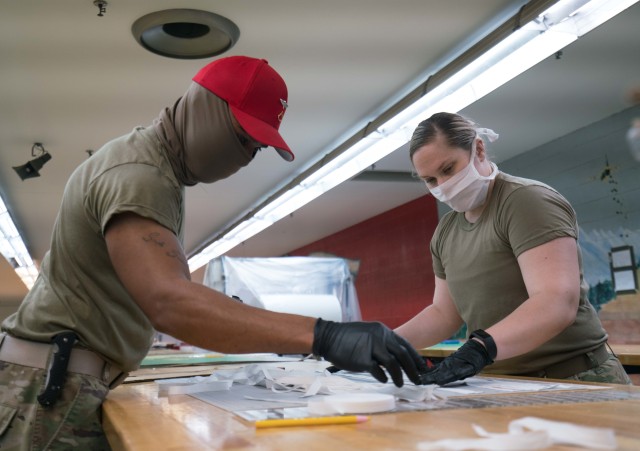 Spc. Ashley George, right, and Pfc. Kevin Cole, left, both parachute riggers with the 647th Quarter Master Company, 3rd Expeditionary Sustainment Command, assemble protective masks at Fort Bragg, N.C., on April 15, during Operation Dragon Mask....