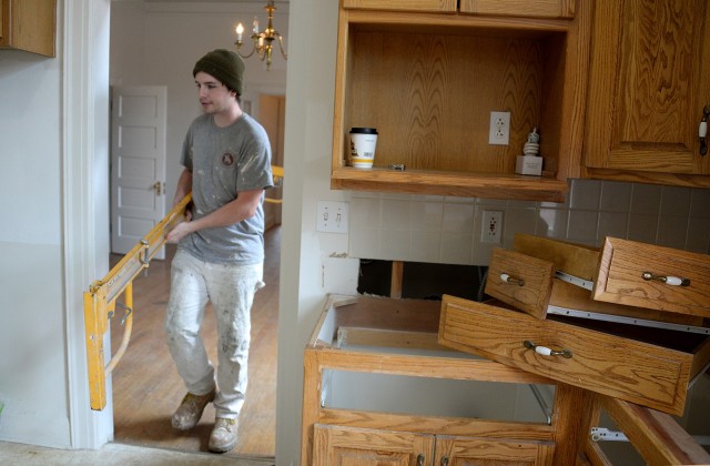 Drake Adams, painter with Fort Leavenworth Frontier Heritage Communities, removes scaffolding from a recently patched and painted room as he exits the Infantry Barracks quarters through the yet-to-be-renovated kitchen March 26. Infantry Barracks quarters are currently undergoing a renovation, to include painted cabinets and new countertops in the kitchens. Photo by Prudence Siebert/Fort Leavenworth Lamp