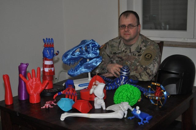 U.S. Army Maj. Brian Mims, senior physician's assistant, 2d Cavalry Regiment sits with several of his 3D printed projects at his home in Vilseck, Germany, April 8, 2020. As a hobby, Mims creates prosthetic arms for children, models, toys, and medical training aids for Soldiers. (U.S. Army photo by Maj. John Ambelang)