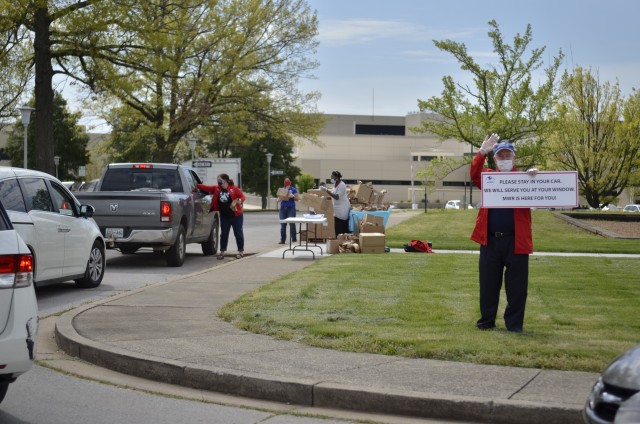 James Moore, supervisory librarian, greets Families as they arrive to pick up bags filled with crafts, April 17 during the Grab-and-Go Brown Paper Bag Craft Giveaway at the Robert F. Sink Memorial Library. Staff from Morale, Welfare and Recreation...